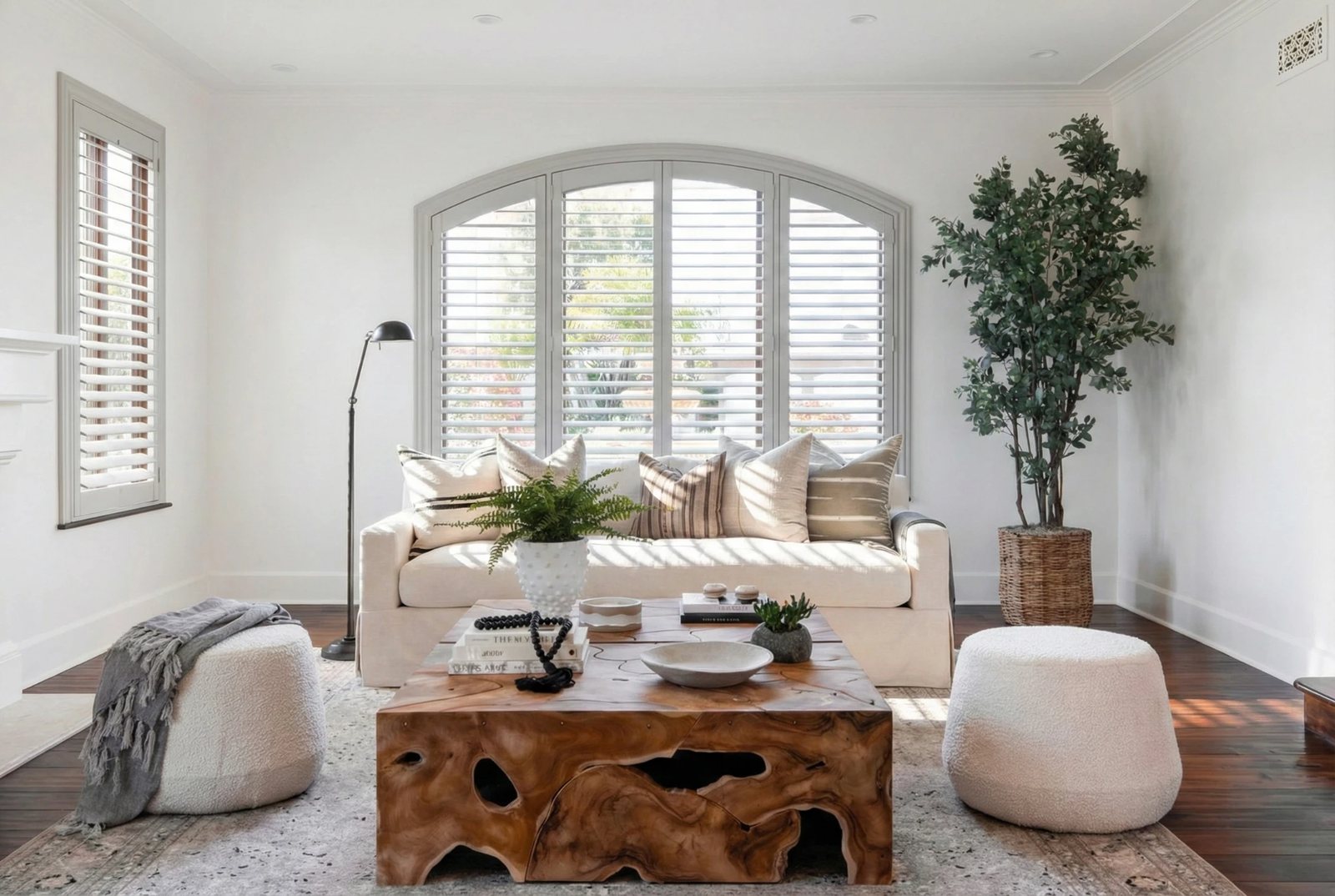 Custom arched white plantation shutters framing a picture window in a bright California living room